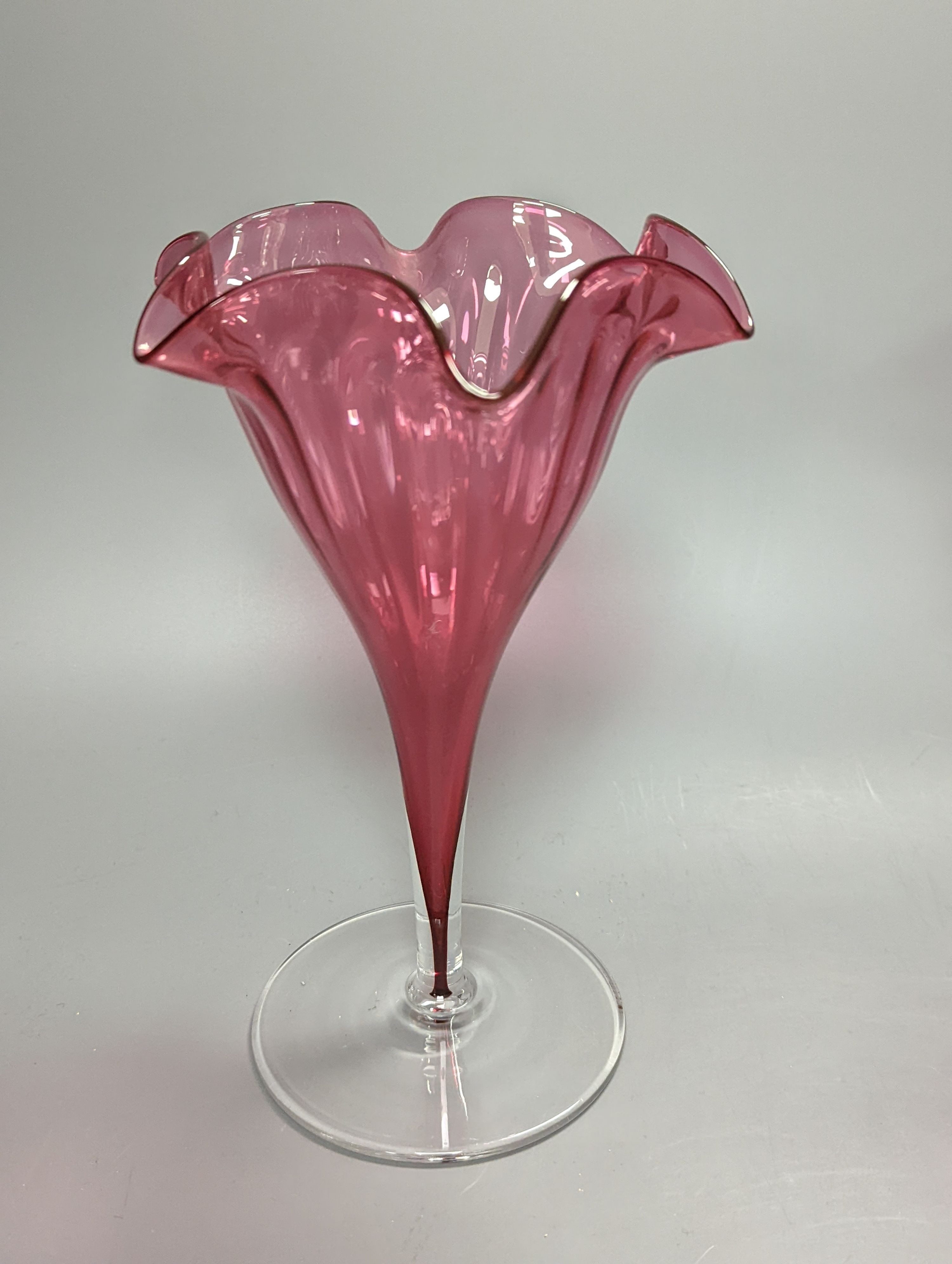 A pair of late Victorian cranberry glass frill vases, height 23cm, and a similar tapering jug